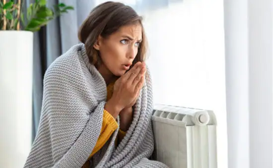 Frau mit Erkältung neben Heizkörper, DANYON® Klimaanlagen für energiesparende Heizung.